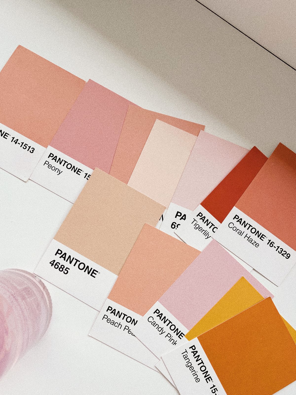 A fan of Pantone colour swatches in peach, coral, and pink