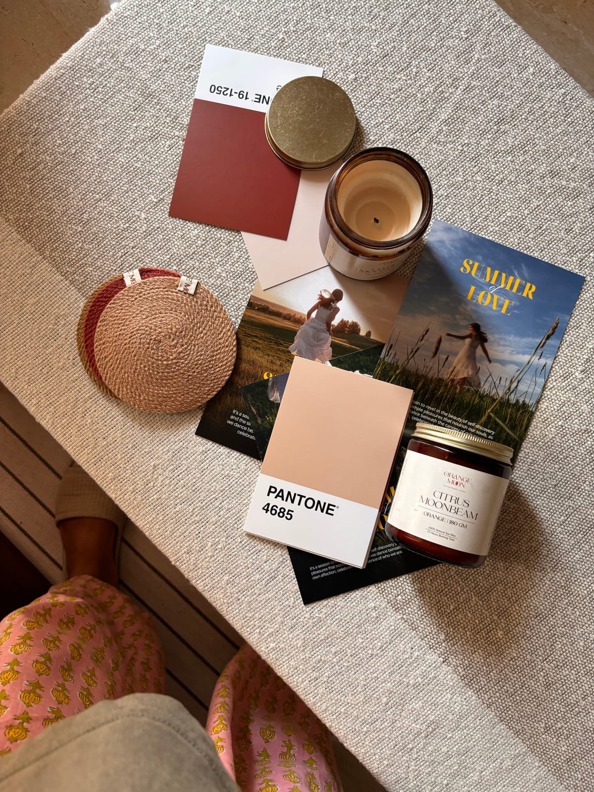 A flatlay mood board with Pantone swatches, a candle, and textured objects